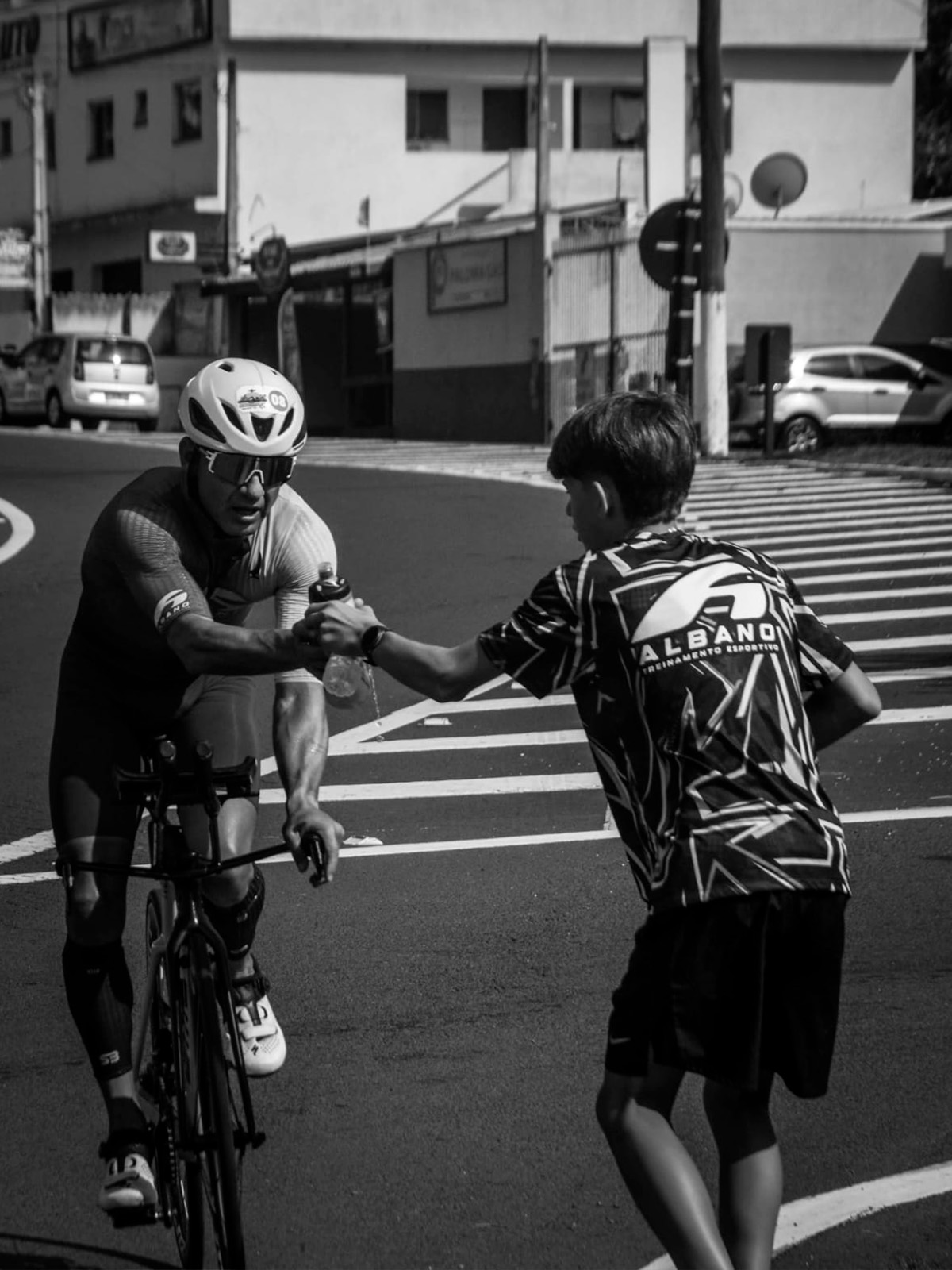 atleta de ciclismo recebendo água de um organizador